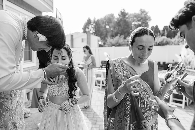 Bride and sister of the bride are being fed by their partners as to not mess up their henna designs.
